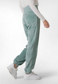 Fleece joggers i blødt grønt, med elastisk talje, sidesømme med kontrastsyning og elastiske manchetter ved anklerne.