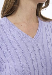 V-Ausschnitt Pullover in helllila, mit einem Kabelstrickmuster und vertikalen Designs. Weiches Strickmaterial mit gerippten Kanten.