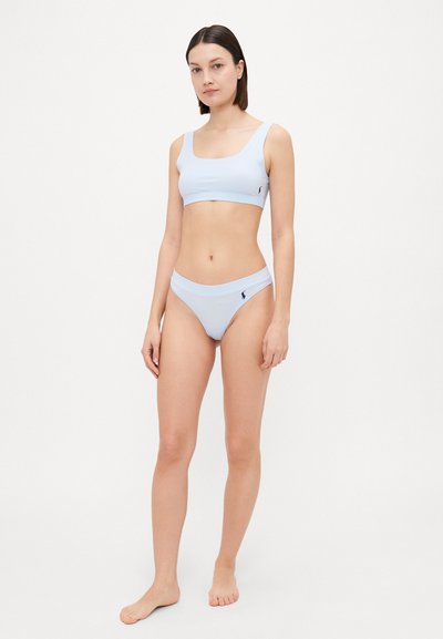 Šviesiai mėlynas bikini rinkinys, pagamintas iš glotnaus audinio, su kvadratine iškirpte viršuje ir žemai atsikabinančiomis kelnaitėmis, kuriose subtiliai pavaizduota logotipo detalė.