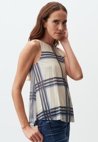 Ärmelloses cremefarbenes Oberteil mit blauem und marineblauem Karomuster, das ein gefaltetes Design aufweist und einen taillierten Körper hat, der am Saum aufspringt.