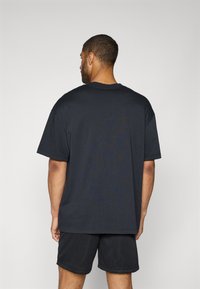 Kortærmet, marineblå t-shirt lavet af bomuld, har en afslappet pasform, rund halsudskæring og glat tekstur, parret med sorte mesh shorts.