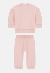 Lichtroze katoenen trainingspak met een sweatshirt met geplooide mouwen en een broek met elastische tailleband en aangenaaide boorden. Zachte textuur, eenvoudig ontwerp.