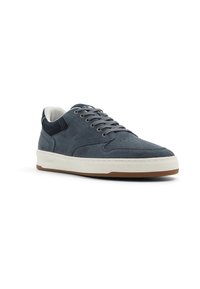 Sneaker in suede grigio con suola in gomma bianca, dotato di una tomaia testurizzata, lacci rotondi e un accento in tessuto blu sulla parte del tallone.