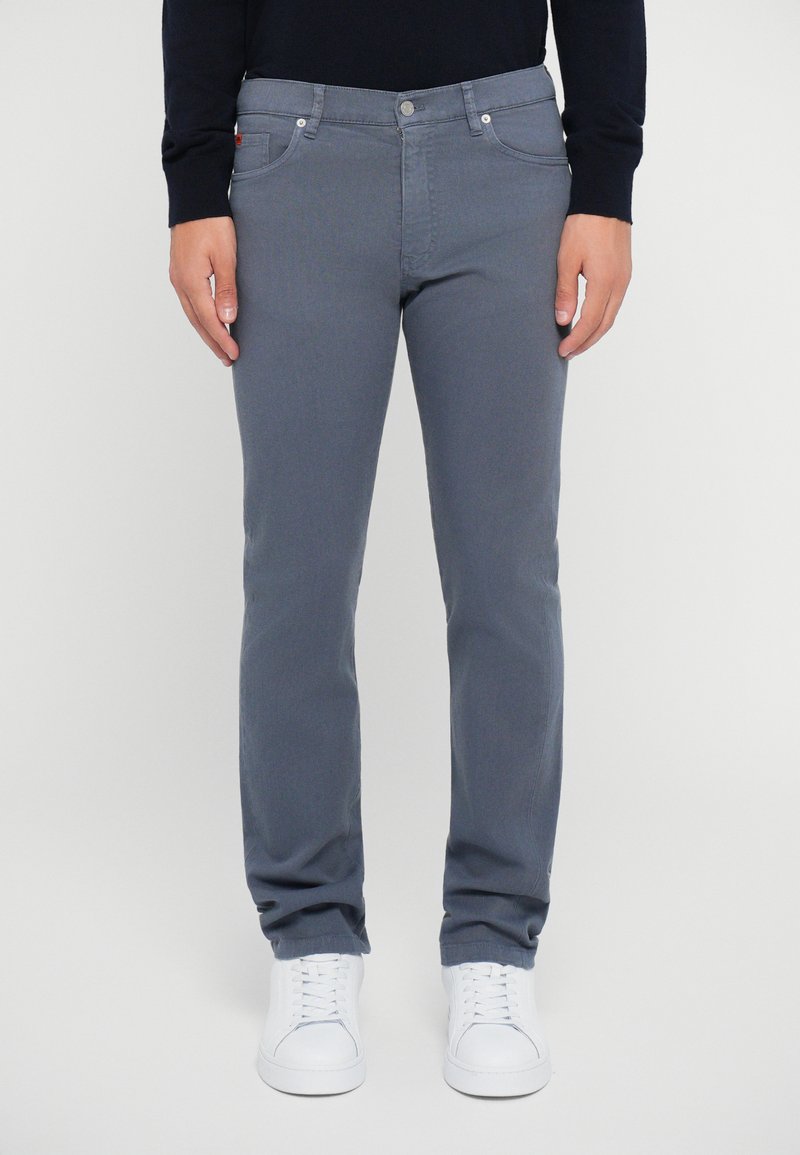 Gray denim trousers with a straight leg, five-pocket design, and metal button closure, paired with white sneakers. Smooth texture.