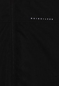 Μαύρο σακάκι από υφασμένο ύφασμα. Διαθέτει φερμουάρ πλήρους μήκους και οριζόντια λευκή ετικέτα λογοτύπου. Λείο υλικό, μινιμαλιστικός σχεδιασμός.