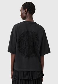 Sort bomulds oversized t-shirt med et struktureret hæklet fredssymbol på ryggen. Korte ærmer og et afslappet pasformdesign.