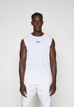 Weißes ärmelloses Oberteil mit schwarzem "BOSS"-Logo, aus glattem Material gefertigt. Das Model trägt passende weiße Hosen und steht vor einem neutralen Hintergrund.