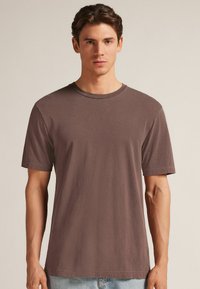 Hnědá bavlněná tričko s kulatým výstřihem a krátkými rukávy. Trošku volnější střih s hladkou texturou, minimálními švy.