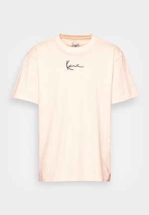 T-shirt à manches courtes couleur crème avec encolure ronde et petit logo noir en écriture manuscrite centré sous le col.