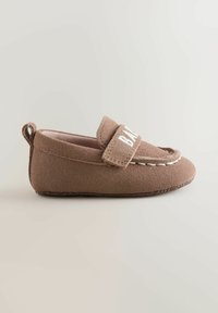Mocassin bébé en daim brun avec coutures blanches et une bride en Velcro étiquetée "BABY", vu de côté sur un fond neutre.
