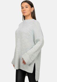 Maglione grigio chiaro a maglia, dalla vestibilità ampia, con maniche ampie e spacchi laterali. Il tessuto testurizzato presenta un motivo a costine ed è morbido al tatto.