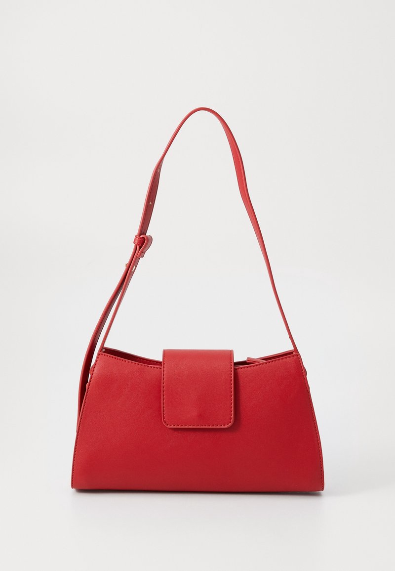 Petit sac à main rouge avec une bandoulière réglable unique et une fermeture à rabat à l'avant sur un fond uni.