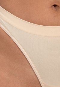 Beige Bikini-Unterteil mit einer glatten, gerippten Textur. Verfügt über ein hohes Schnittdesign und einen breiten, elastischen Bund für zusätzlichen Komfort.