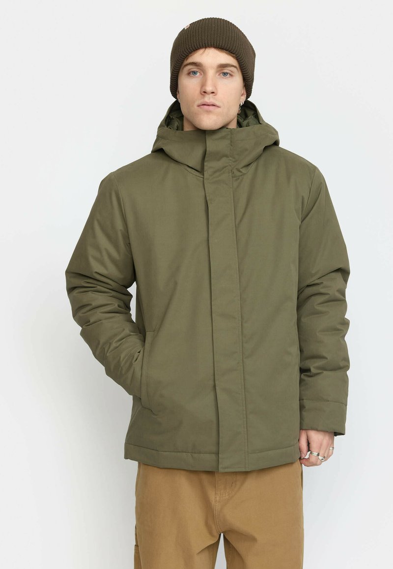Olive green insulated jacket with a high collar and attached hood, featuring a front zipper and side pockets. Textured fabric.
