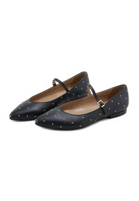 Bailarinas de cuero negro con punta afilada, adornadas con pequeños studs dorados, con una delgada correa en el tobillo y suela plana.