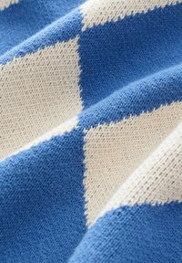 Blå og creme strikket stof med et diagonalternet mønster. Blød tekstur med synlige sting og let varierende garn tykkelse.