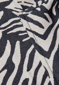 Cotton fabric featuring a bold black and white zebra stripe pattern, with a smooth texture and sharp contrasts between colors.
