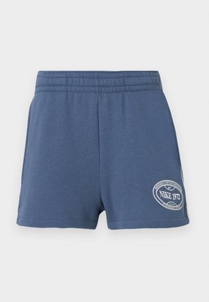 Niebieskie spodenki z elastycznym pasem i naszywką z logo Nike 1972 na dole lewej nogawki na jednolitym tle.
