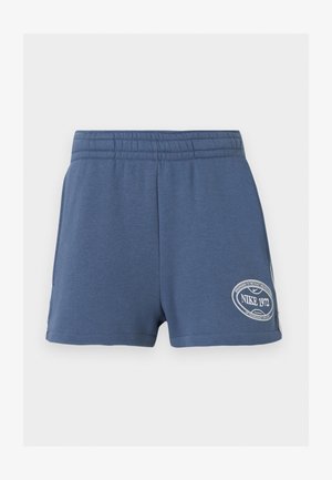 Niebieskie spodenki z elastycznym pasem i naszywką z logo Nike 1972 na dole lewej nogawki na jednolitym tle.