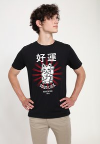 Černé bavlněné tričko s grafickým designem kočky se zvednutou tlapkou, červenými paprsky a textem "Good Luck Ramen Bar Tokyo."