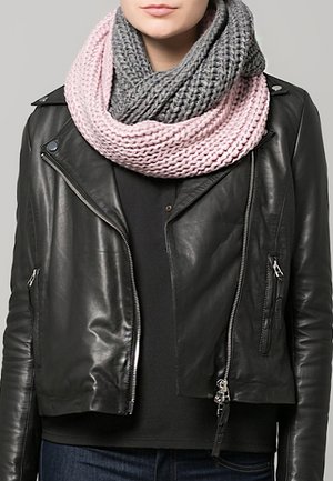 Femme portant une écharpe infinie en tricot épais bicolore rose et gris, sur une veste en cuir noire et un haut foncé.