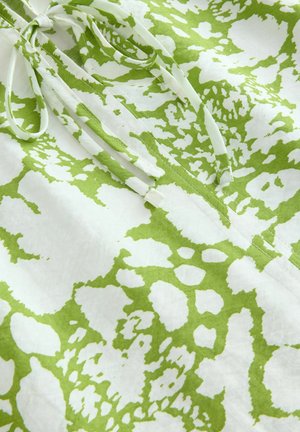 Țesătură cu model verde și alb, cu un amestec de forme neregulate. Prezintă legături la gât, realizate din material ușor.