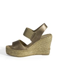 Sandale en bronze avec un design peep-toe, une bride élastique et une plateforme en jute tissé. Fini métallique lisse et bases texturées.