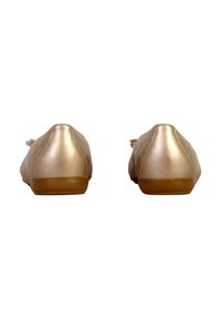 Bailarinas en dorado rosa con una textura suave, puntera redonda y suelas de goma planas. Los lazos en la parte frontal realzan el diseño minimalista.
