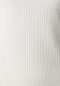 Biały prążkowany materiał o gładkiej fakturze, z pionowymi paskami. Tkanina wydaje się miękka i drobno tkana, odpowiednia do dopasowanej odzieży.