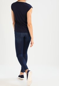 Námořnická modrá krátká halenka s kulatým výstřihem, spárovaná s tmavě modrými skinny džínami a námořnickými plátěnými bezpodrážkovými botami.