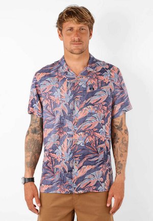 Chemise à manches courtes avec un fond bleu et des motifs de feuilles tropicales roses et bleu clair. Front boutonné et une poche poitrine.