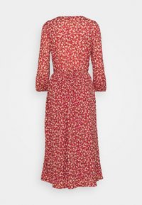 Rød blomstret kjole med en tætsiddende talje, lange ærmer og en udvidet kant. Stoffet har et tekstureret og let udseende med små hvide og cremefarvede blomster.