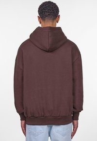 Brun hætte sweatshirt med en afslappet pasform, ribbede manchetter og kant samt en blød tekstur. Bagsiden har et enkelt design uden tryk.