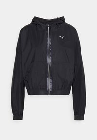 Veste coupe-vent noire avec capuche, fermeture éclair, poignets élastiques et deux poches avant. Présente un petit logo sur la poitrine gauche.