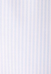 Gros plan d’un tissu clair avec des rayures verticales bleues et blanches et de petits motifs pointillés en rangées alternées.