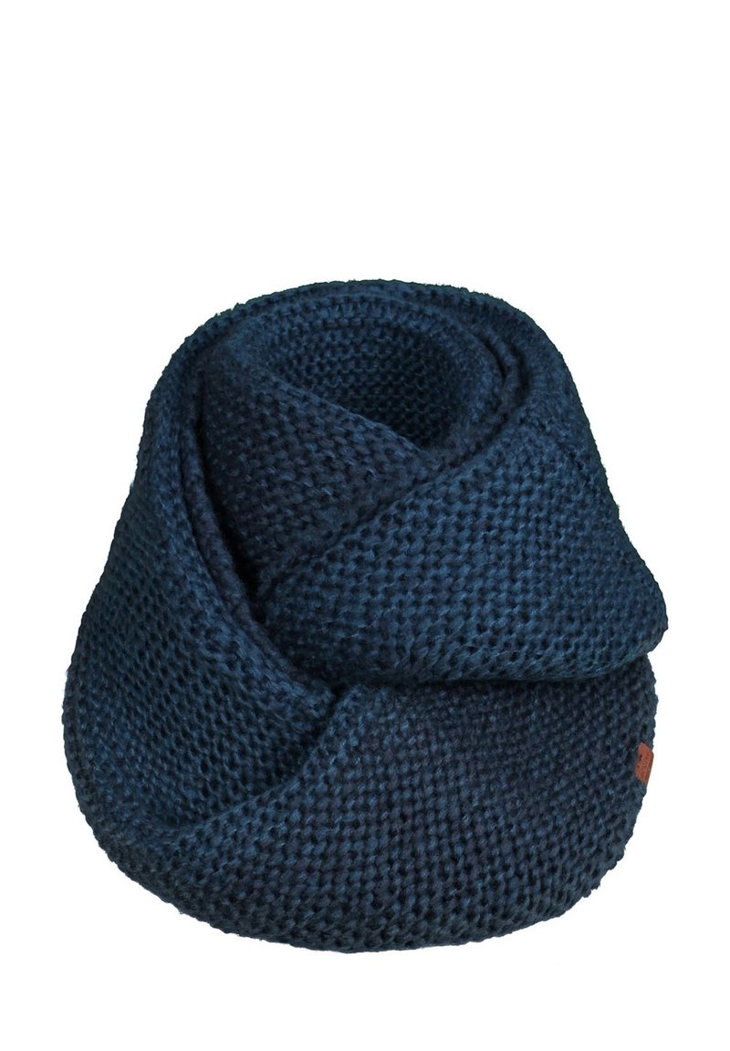 Écharpe infinie en grosse maille bleu foncé, enroulée sur un fond blanc avec une petite étiquette marron.