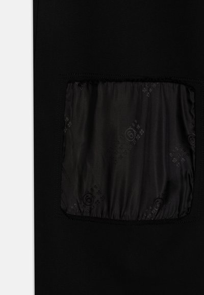 Svart tyg med en slät finish, med en fyrkantig ficka av glänsande material som har präglade siffror och former.