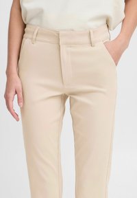Beige skräddarsydda byxor med en mjuk textur, med hög midja, sidofickor och en veck fram för en strukturerad look.