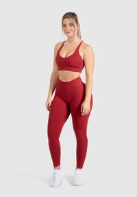 Rode sportset met een effen sportbeha en hoge taillelegging, gemaakt van een gladde, rekbare stof voor comfort en ondersteuning.