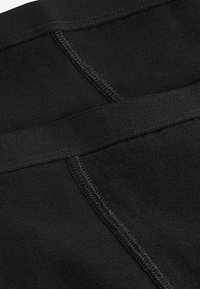 Schwarzer dehnbarer Stoff mit glatter Textur, der kontrastierende Nähte und einen breiten elastischen Bund aufweist. Ideal für Sportbekleidung oder Freizeitmode.