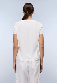 Hvid t-shirt med rund halsudskæring og korte ærmer, fremstillet af blødt bomuld. Bageste udsigt fremhæver den glatte tekstur og det enkle design.