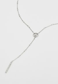 Silver necklace with elongated links, central circular motif, and a vertical pendant set with small stones, creating a minimalist design.
