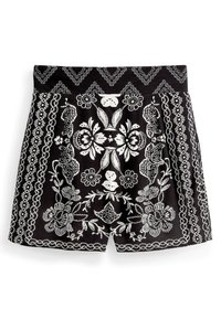 Shorts noirs avec broderie florale blanche et motifs géométriques, dotés d'une large ceinture et d'un design plissé pour plus de texture.