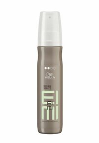 Wella EIMI Ocean Spritz salt spray i en brun cylindrisk flaska med en klar pump-top, med en mintgrön etikett och vit logotyp.