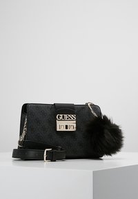 Sort Guess handbag med tekstureret materiale, guldhardware, logo-plade og aftagelig pels pom-pom. Inkluderer en aftagelig rem.