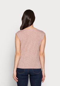 Lys pink farvet ærmeløs top med struktureret mønster, der ligner striber, fremstillet af blødt materiale. Bagfra ses en rund halsudskæring.