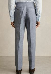 Pantaloni din in de culoare bleu deschis, cu croi drept, având două buzunare la spate și nasturi negri, pe un fundal neutru.