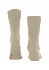 Calzini beige con una bordatura a costine, texture liscia e tallone definito. Presentano il marchio FALKE sulla suola. Design classico di altezza media fino al polpaccio.