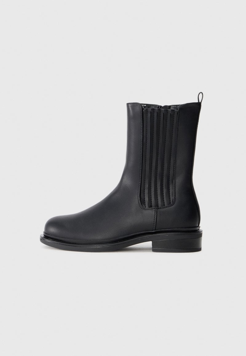 Botte Chelsea en cuir noir avec panneaux latéraux élastiques, languette à l'arrière, bout arrondi et petit talon empilé.