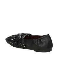 Scarpa piatta nera con punta affilata, realizzata in pelle. Presenta punte metalliche, un design intrecciato sulla parte anteriore e un retro elasticizzato per il comfort.